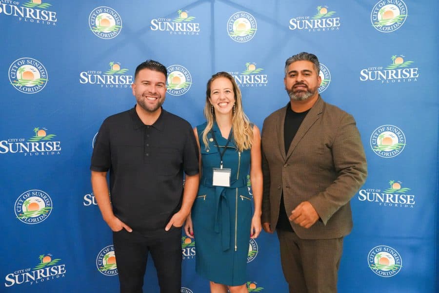 Carlos Gil with Summit guests in front of the City of Sunrise backdrop