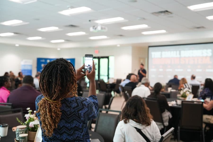An attendee films the talk on her phone as the Growth System slide is shown